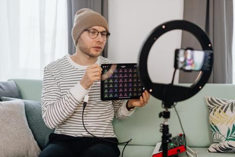 Guy with cap and glasses talks to his phone on a tripod with a ring light