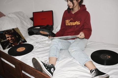 Girl sitting on a bed with record albums spread out