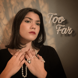 Girl wearing black top and pearl necklace has hands on neck while looking forward Girl wearing black top and pearl necklace has hands on neck while looking forward