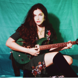 Lolva Aviva seated and holding her electric guitar Lola Aviva seated and holding her electric guitar