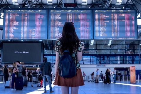 Girl standing in airport looks up at arrival and departure screens Girl standing in airport looks up at arrival and departure screens