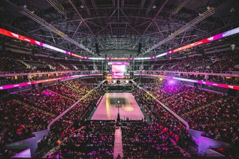 A big crowd is in a huge arena where a basketball game is being played