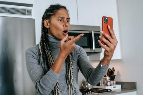 Girl holding up and looking at smartphone with appalled look on her face Girl holding up and looking at smartphone with appalled look on her face