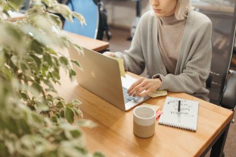 Female sitting at her laptop on a table Female sitting at her laptop on a table