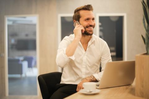 Guy, seated at his laptop, talking on the phone