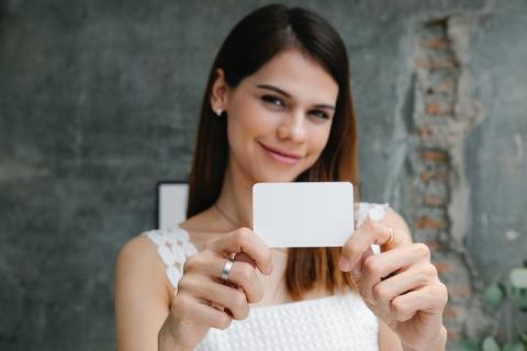 Girl holding white business card out towards camera Girl holding white business card out towards camera