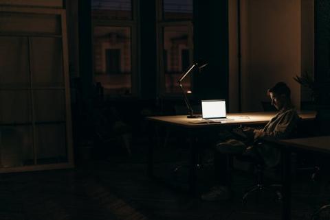 Guy sitting at his desk alone in a dark office seemingly late at night Guy sitting at his desk alone in a dark office seemingly late at night