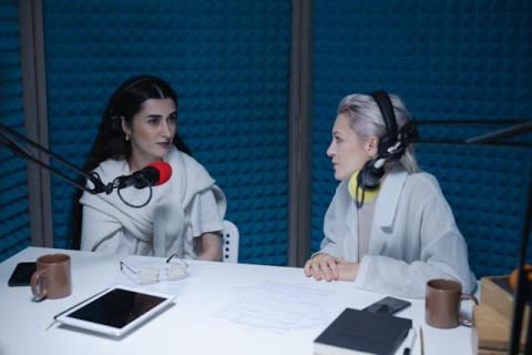 Two girls wearing headphones and sitting at microphones in a padded studio Two girls wearing headphones and sitting at microphones in a padded studio