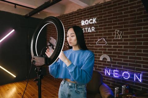 Girl with long black hair holding smartphone next to ring light