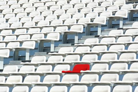 One red seat in stadium full of white seats One red seat in stadium full of white seats