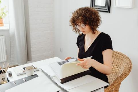 Girl seated in home office looking at a file Girl seated in home office looking at a file