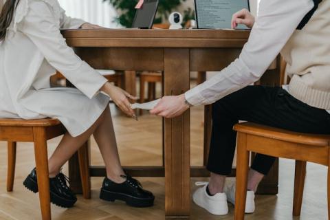 Two hands passing a note to each other under a table Two hands passing a note to each other under a table