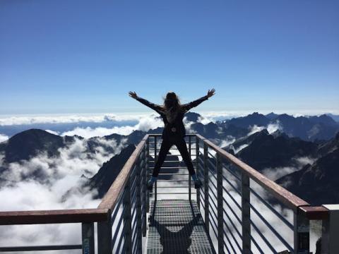 Female with arms raised up high at a mountainous lookout point Female with arms raised up high at a mountainous lookout point