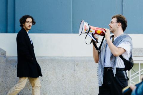 A man speaks through a megaphone while a passerby looks his way