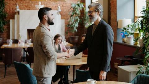 Two men shaking hands in a coffee shop Two men shaking hands in a coffee shop