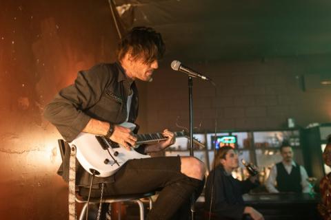 Musician sitting on stage playing guitar