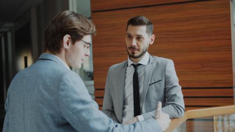 Two men are talking to one another and looking serious almost in an advisory posture