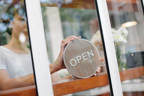 Girl putting OPEN sign in shop window