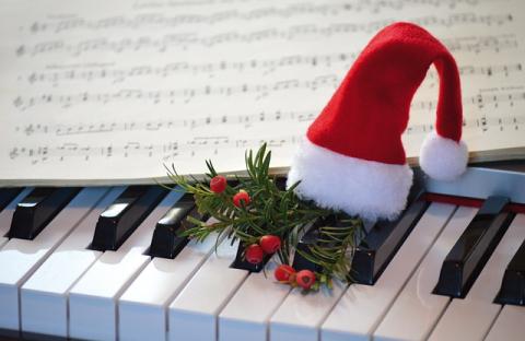 Sheet music and tiny Santa hat on piano keys Sheet music and tiny Santa hat on piano keys